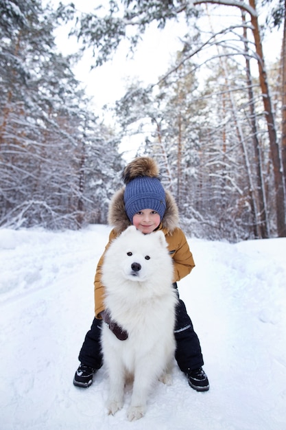 a boy with a dog in the winter forest