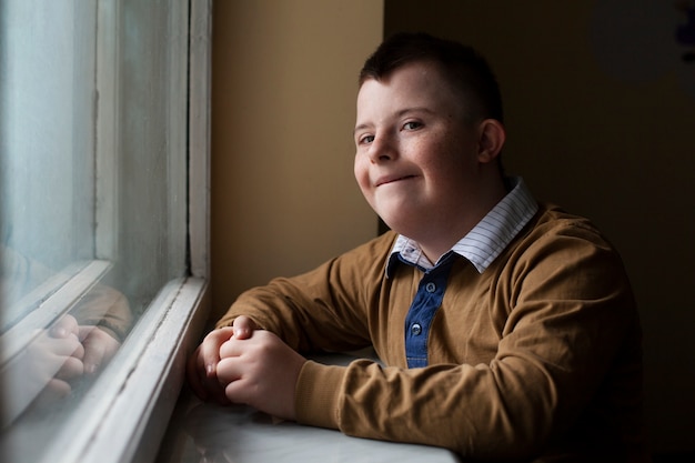 Boy with down syndrome posing by window