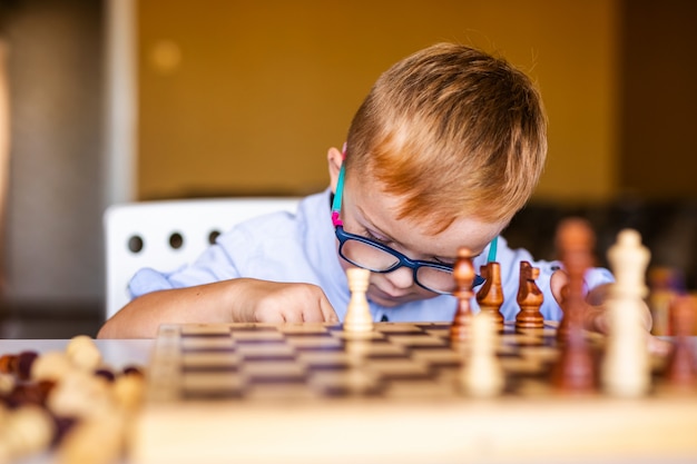 Boy with down syndrome with big glasses playing chess