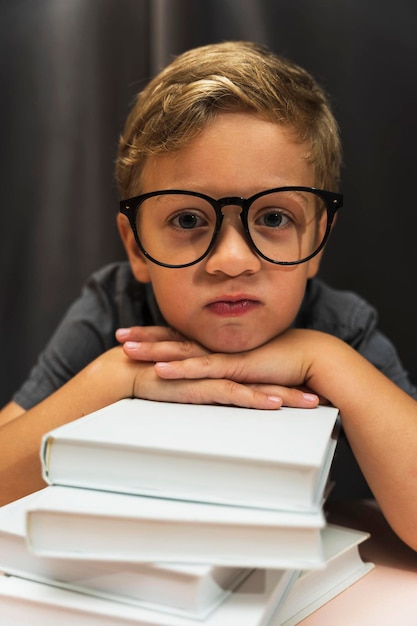 A boy with glasses and a stack of books back to school study fatigue study difficulties