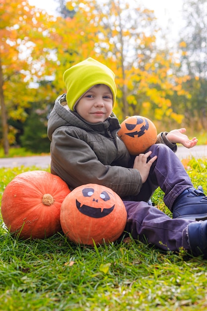 A boy with a Halloween pumpkin with eyes . The feast of fear. Halloween. An orange pumpkin with eyes.