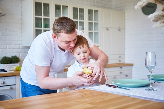 Boy with his father in the kitchen. The child eats an apple. The concept of family and fatherhood.