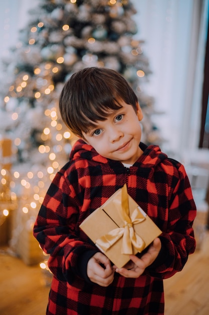 A boy with a New Year's gift under the tree lifestyle. New Year and Christmas. Festive decoration.