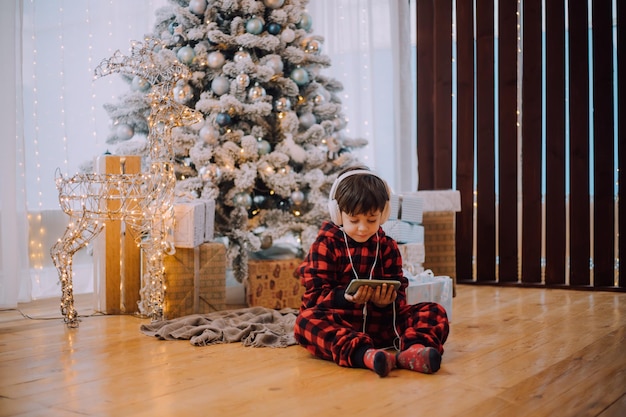 The boy with the phone under the Christmas tree lifestyle. New Year and Christmas.