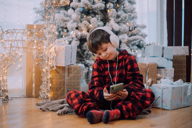 The boy with the phone under the Christmas tree lifestyle. New Year and Christmas.