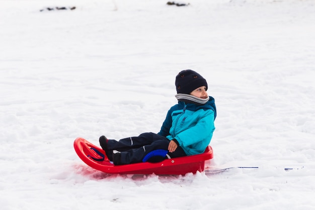 A boy with red sled in the snow