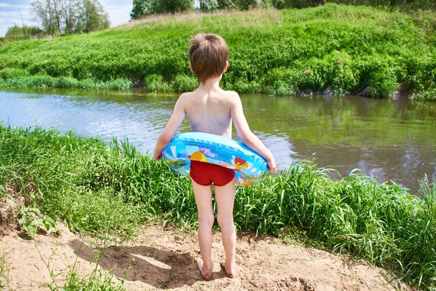 Boy with toy lifebuoy for swimming near river