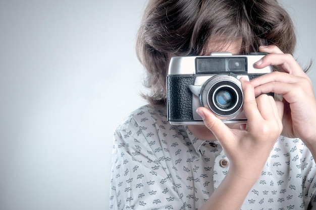 Boy with white shirt and blue details taking pictures with antique camera