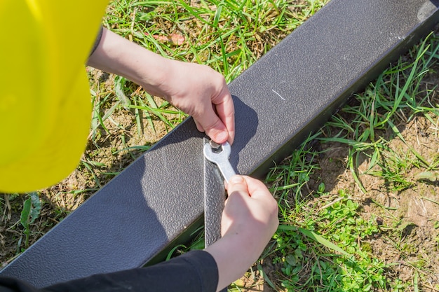 Boy in yellow ÃÂÃÂÃÂ· with a hand tool assembling metal construction outdoors