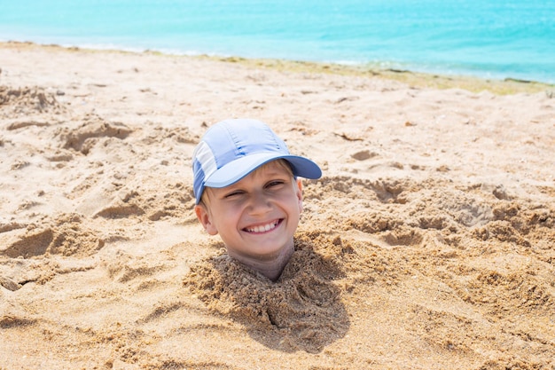 The boy39s head sticks out of the sand Fun weekend at the seaside