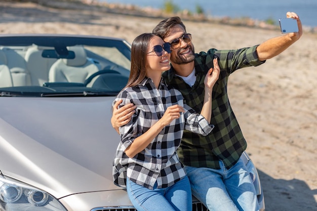 Boyfriend and girlfriend taking selfie and sitting on the cabriolet