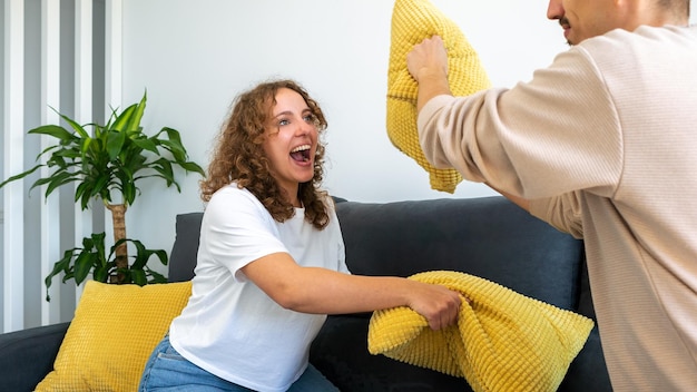 Boyfriends having fun playing together on sofa at home fighting with cushion