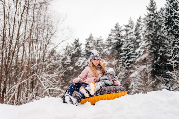 Boys and a girl are sitting in a tubing in the snow