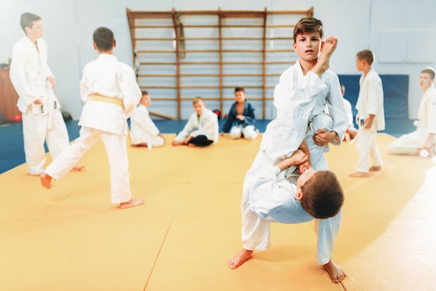 Boys in kimono fights, kid judo training. Young fighters in gym, martial art for defense