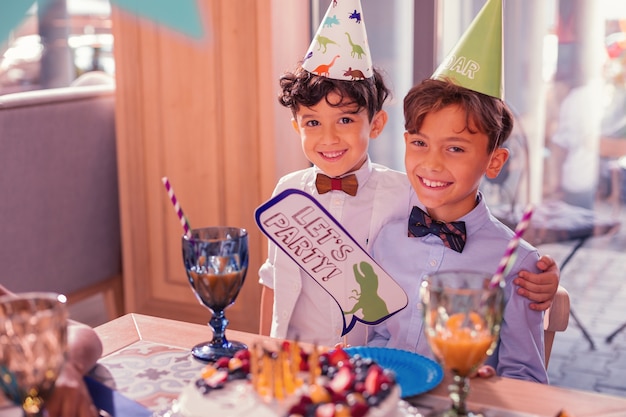 Boys wearing party hats in front of delicious cake