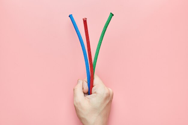 Braided nylon ropes in hand. Red, green and blue end of ropes in male hand as gift concept.