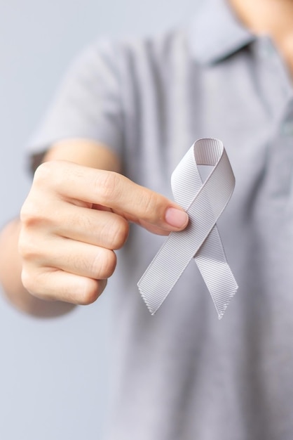 Brain Cancer Awareness month woman hand holding grey color Ribbon for supporting people life Healthcare and World cancer day concept