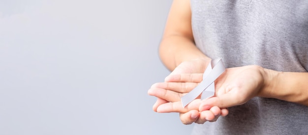 Brain Cancer Awareness month woman hand holding grey color Ribbon for supporting people life Healthcare and World cancer day concept