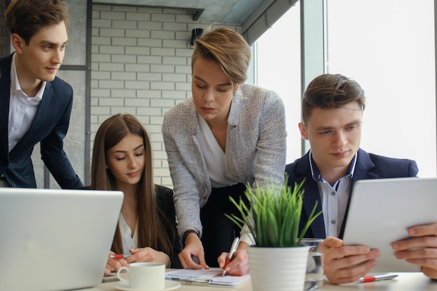 Brainstorm Group of business people looking at the laptop together One business woman looking at camera