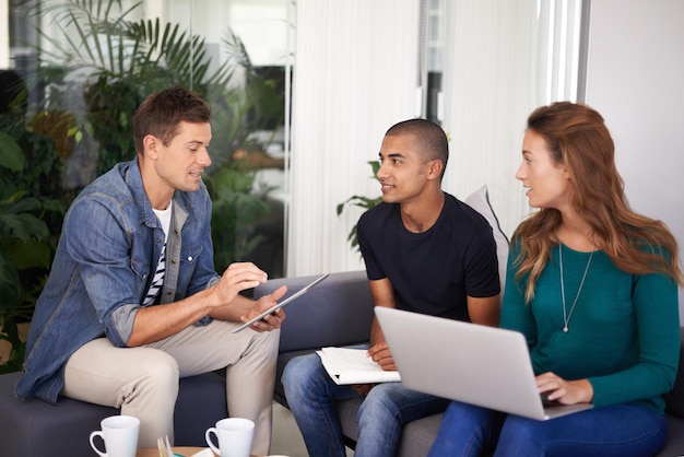 Brainstorming some ideas A team of young business professionals using technology in an informal meeting