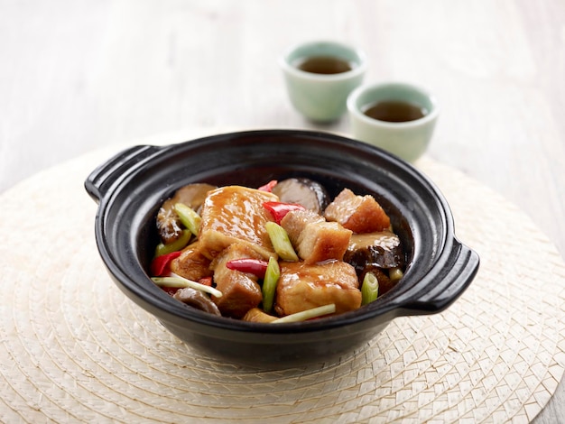 Braised Tofu with Shrimp Paste and Pork Belly in with chopsticks served in a Claypot isolated on mat side view on grey background