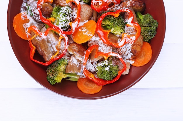 Braised wild mushrooms with vegetables and sauce in plate on table