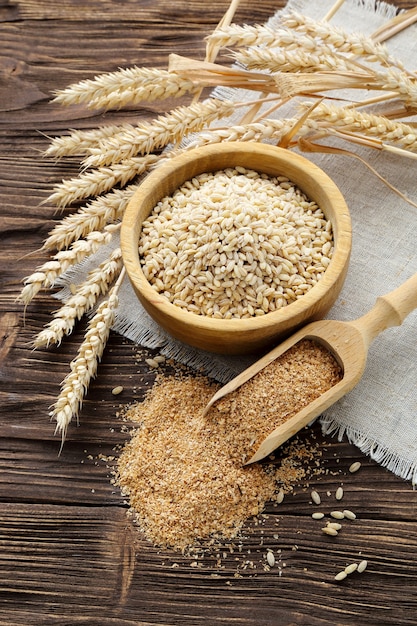 Bran, grain and wheat ears on a brown wooden table