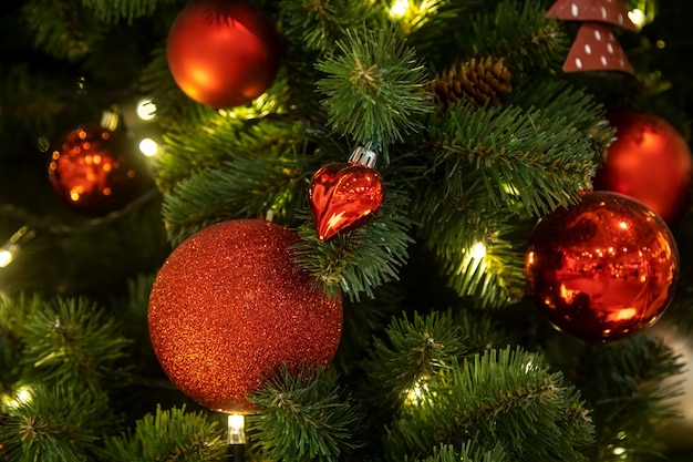 a branch of a christmas tree decorated with red balls with toys