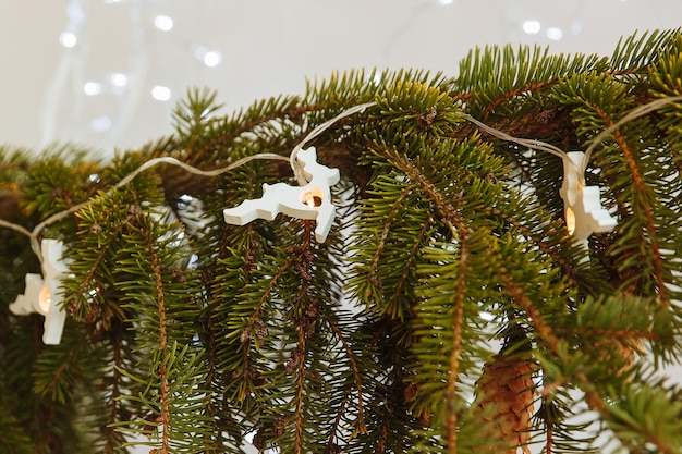 a branch of a Christmas tree with a garland in the form of deer