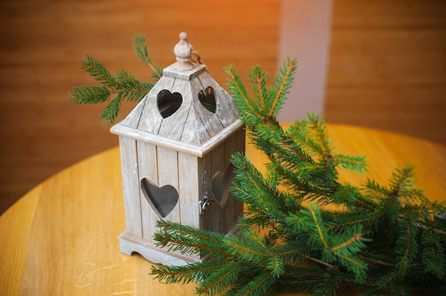 Branch of Christmas trees and white wooden candlestick on the table