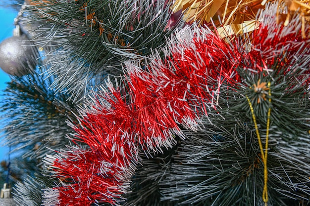 The branch of a festive Christmas tree is decorated with red glittering tinsel