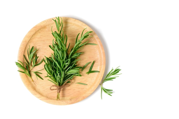 Branch of fresh rosemary on wood plate isolated on white background