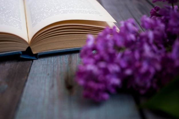 Branch of lilac and opened book on a wooden background