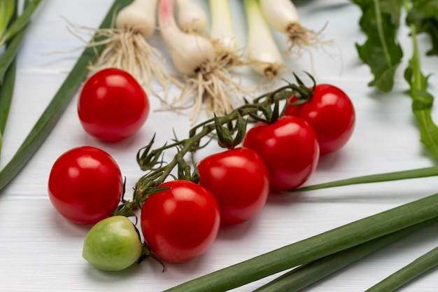 Branch of tomato green onions with roots and arugula