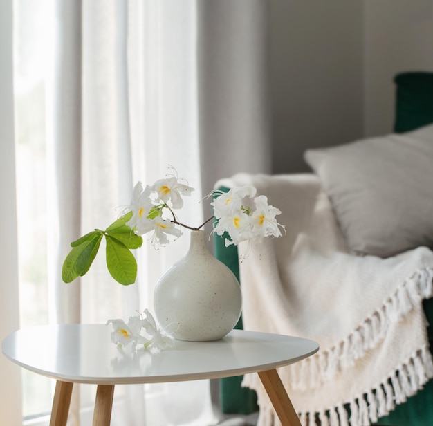 Branch of white rhododendron in vase in modern cozy interior