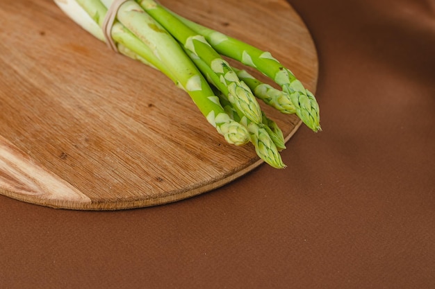 Branches of fresh green asparagus on a wooden board brown background top view Basic trend concept with copy space