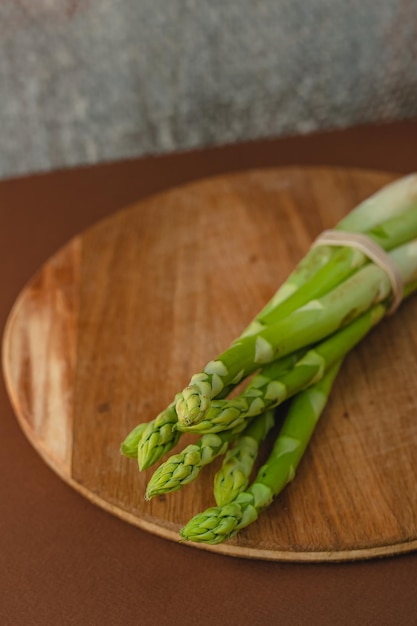 Branches of fresh green asparagus on a wooden board brown background top view Basic trend concept with copy space