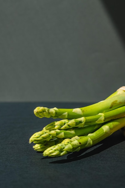 Branches of fresh green asparagus on a wooden board dark gray background top view Basic trend concept with copy space