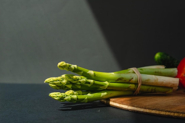 Branches of fresh green asparagus on a wooden board dark gray background top view Basic trend concept with copy space