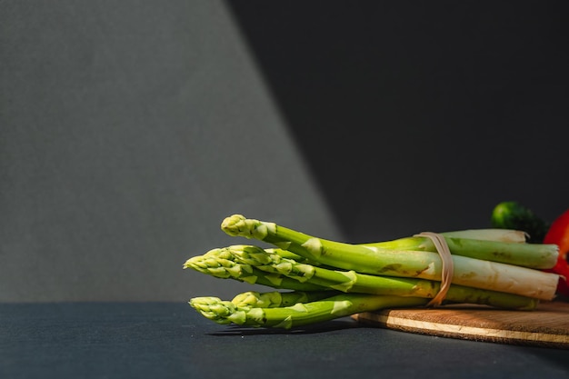 Branches of fresh green asparagus on a wooden board dark gray background top view Basic trend concept with copy space