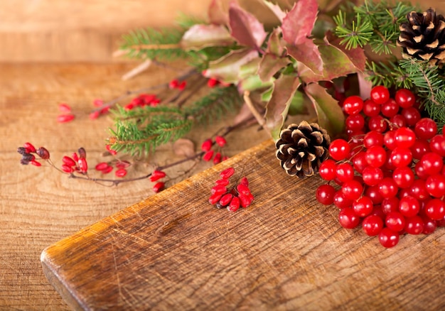 Branches of holly pine cones mountain ash berries on wooden background