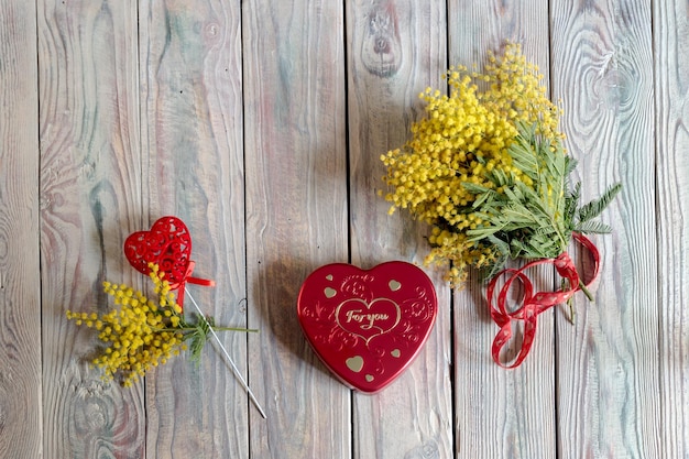 Branches of yellow mimosa and box of chocolates