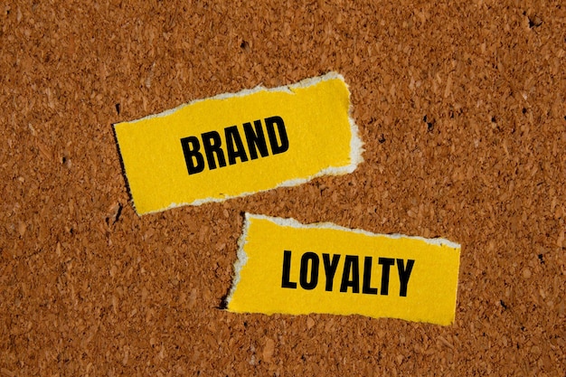 Brand loyalty words written on ripped yellow paper with brown background