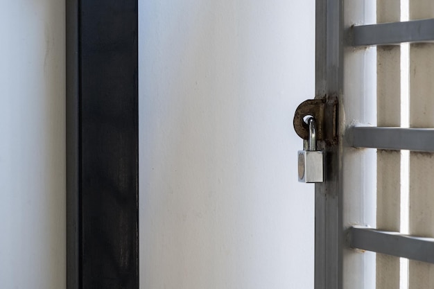 The brass padlock locks the metal fence of the urban house for safety and privacy, front view with the copy space.