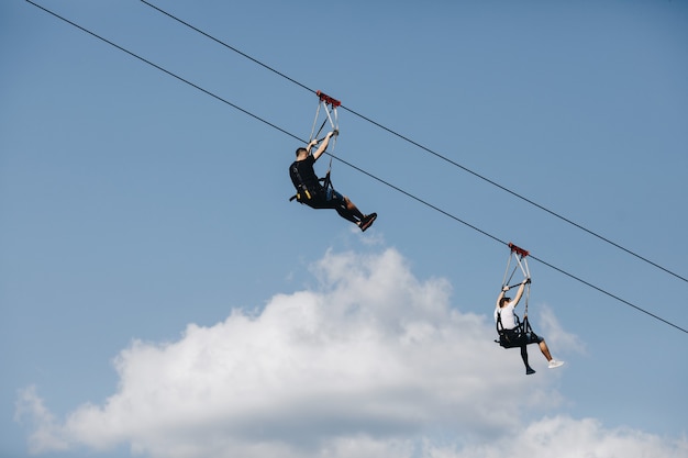 A brave man descends on a zip line high in the mountains above the forest.