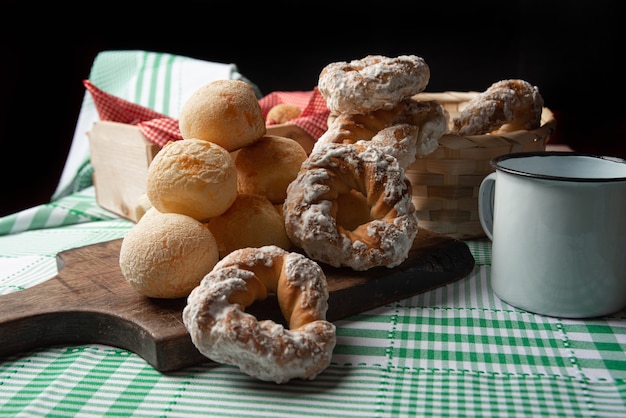 Brazil cheese bread and sweet biscuit and a cup of coffee on a table with green checkered tablecloth, selective focus.