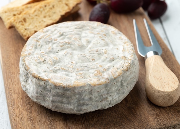 Brazilian artisan Bofete blue cheese with bread nuts and fruits over wooden table