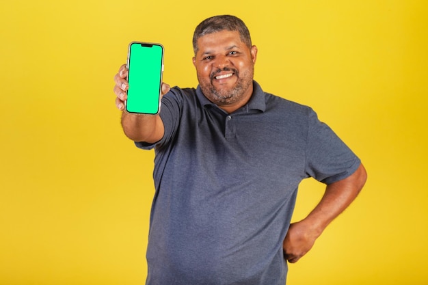 Brazilian black man adult pointing at cellphone screen negative space for advertisement