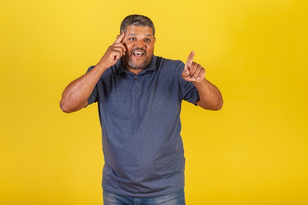 Brazilian black man adult pointing something distant with his finger surprised