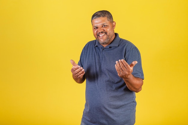 Brazilian black man adult smiling inviting with his hands calling come